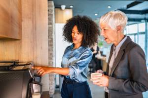 Two colleagues making a fresh milk coffee at an office bean-to-cup machine