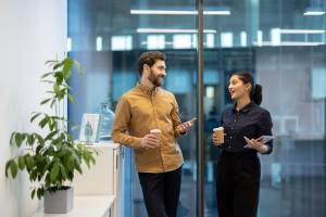 Two colleagues away from their desks holding takeaway coffee cups
