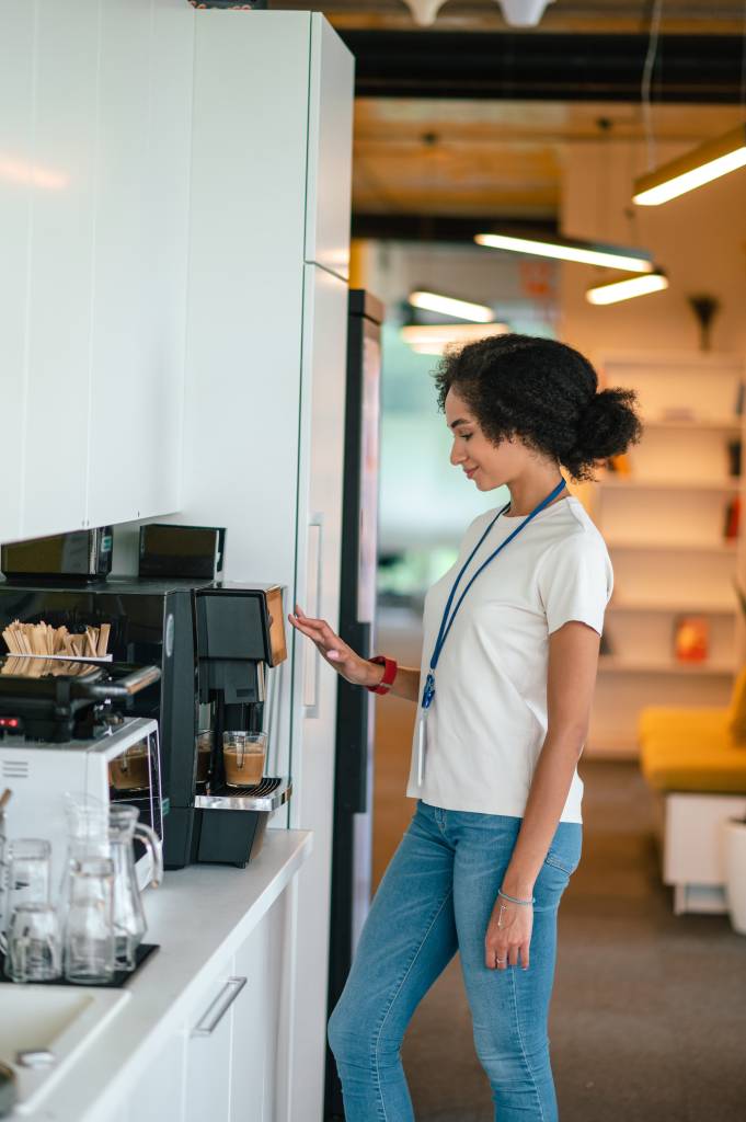 A colleague making a fresh coffee in an office break room