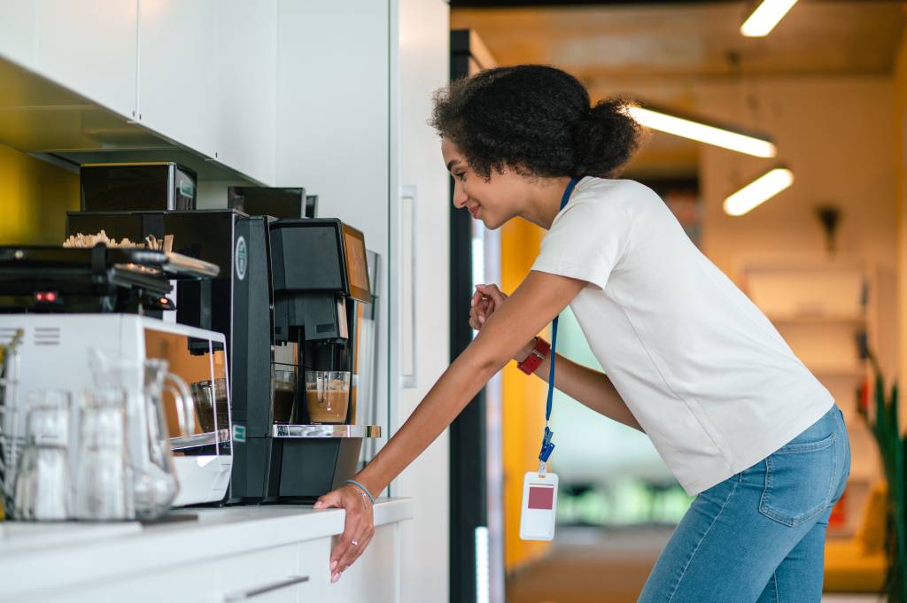 An employee making her own coffee at the office machine