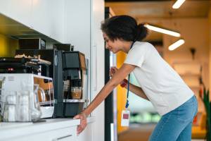 An employee making her own coffee at the office machine