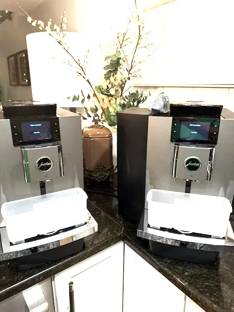 Two JURA X10 bean-to-cup coffee machines on an office breakroom counter