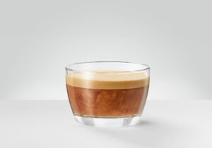 A flat white in a wide low cup, espresso beneath a thin glossy layer of steamed milk