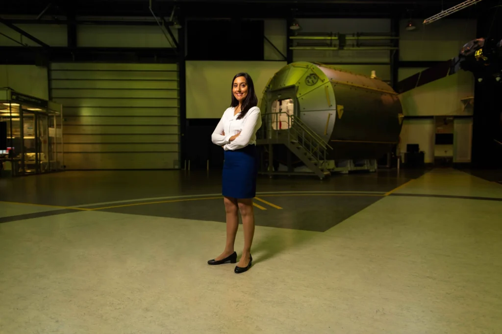 An engineer standing in an aerospace hangar beside a large fuselage section