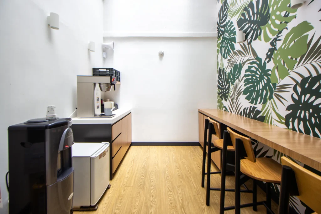 A bright office kitchenette with a filter coffee brewer, water cooler and a long breakfast bar