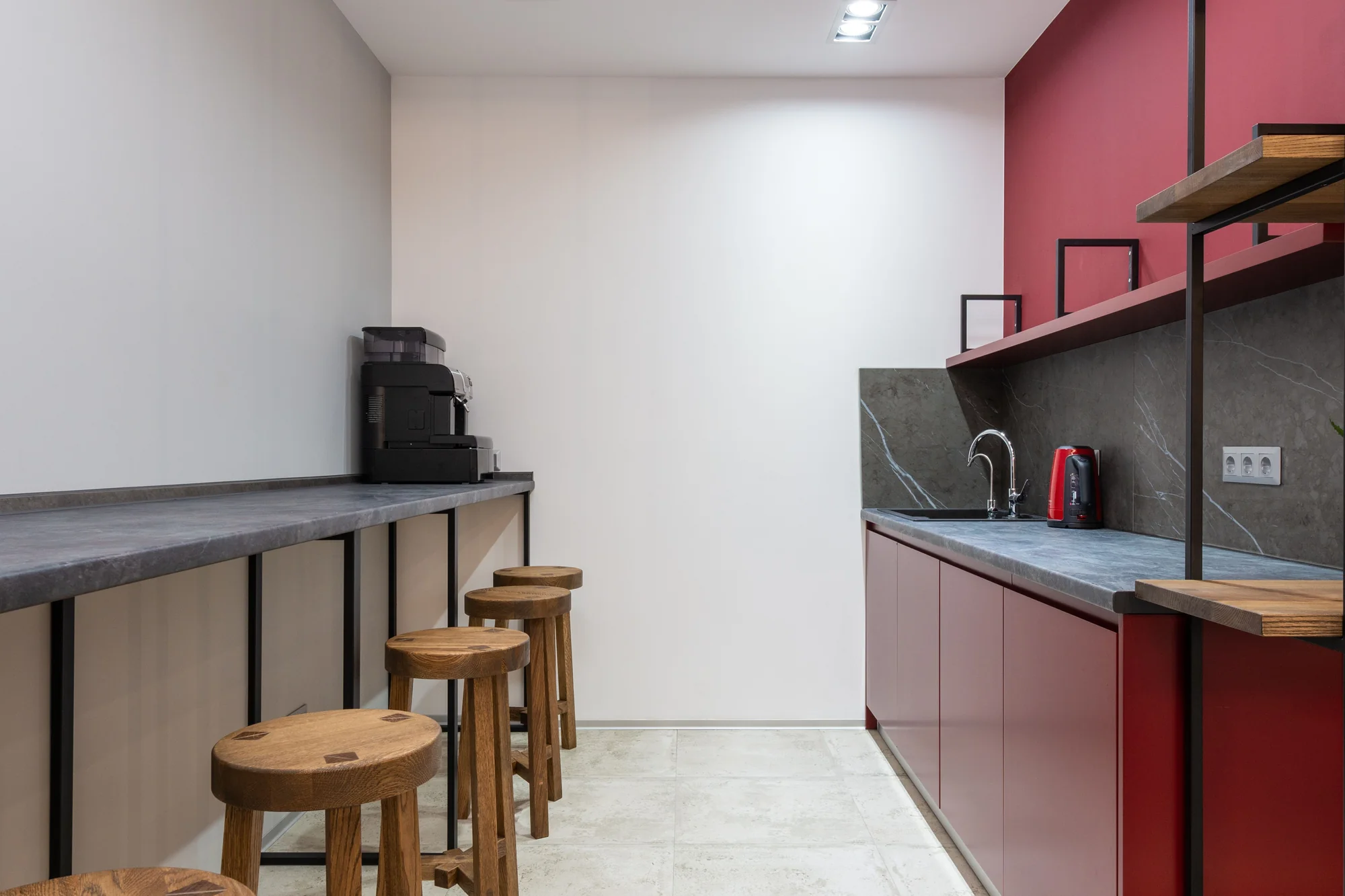 An office pantry with a bean-to-cup coffee machine on a long counter and stools alongside