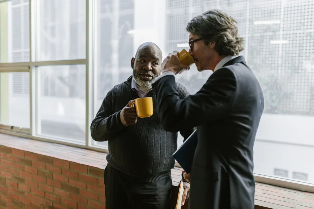 Two colleagues drinking coffee together at an office window